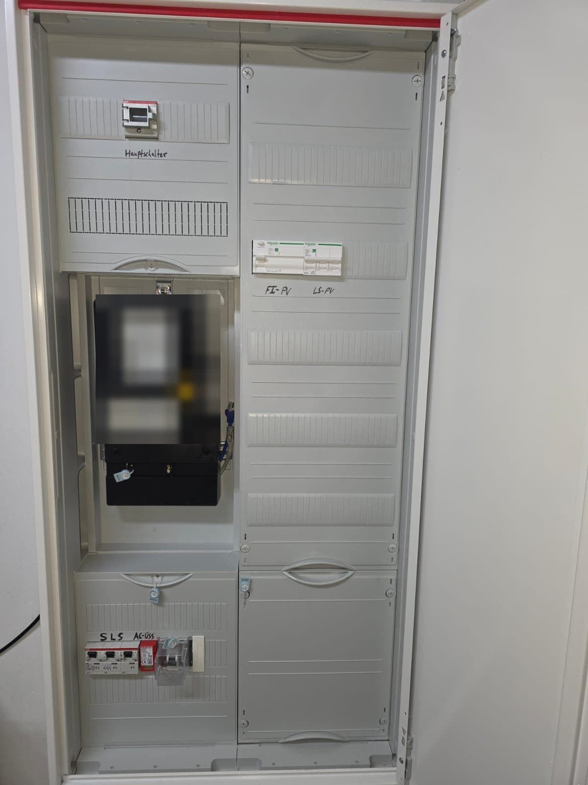 Offener neuer Zählerschrank: oben links der Hauptschalter, darunter der Zähler, rechts die beschrifteten Schalter FI-PV und LS-PV, unten links der SLS-Schalter